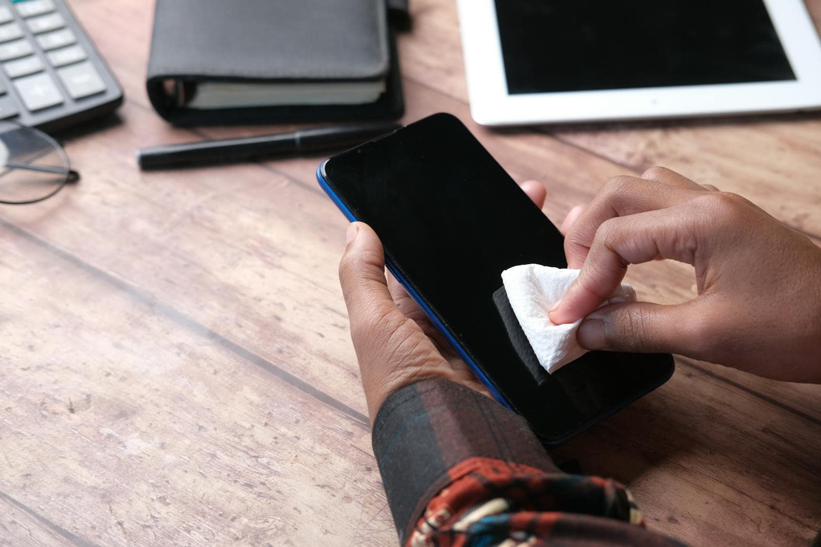 A technician carefully cleaning a smartphone with a cloth