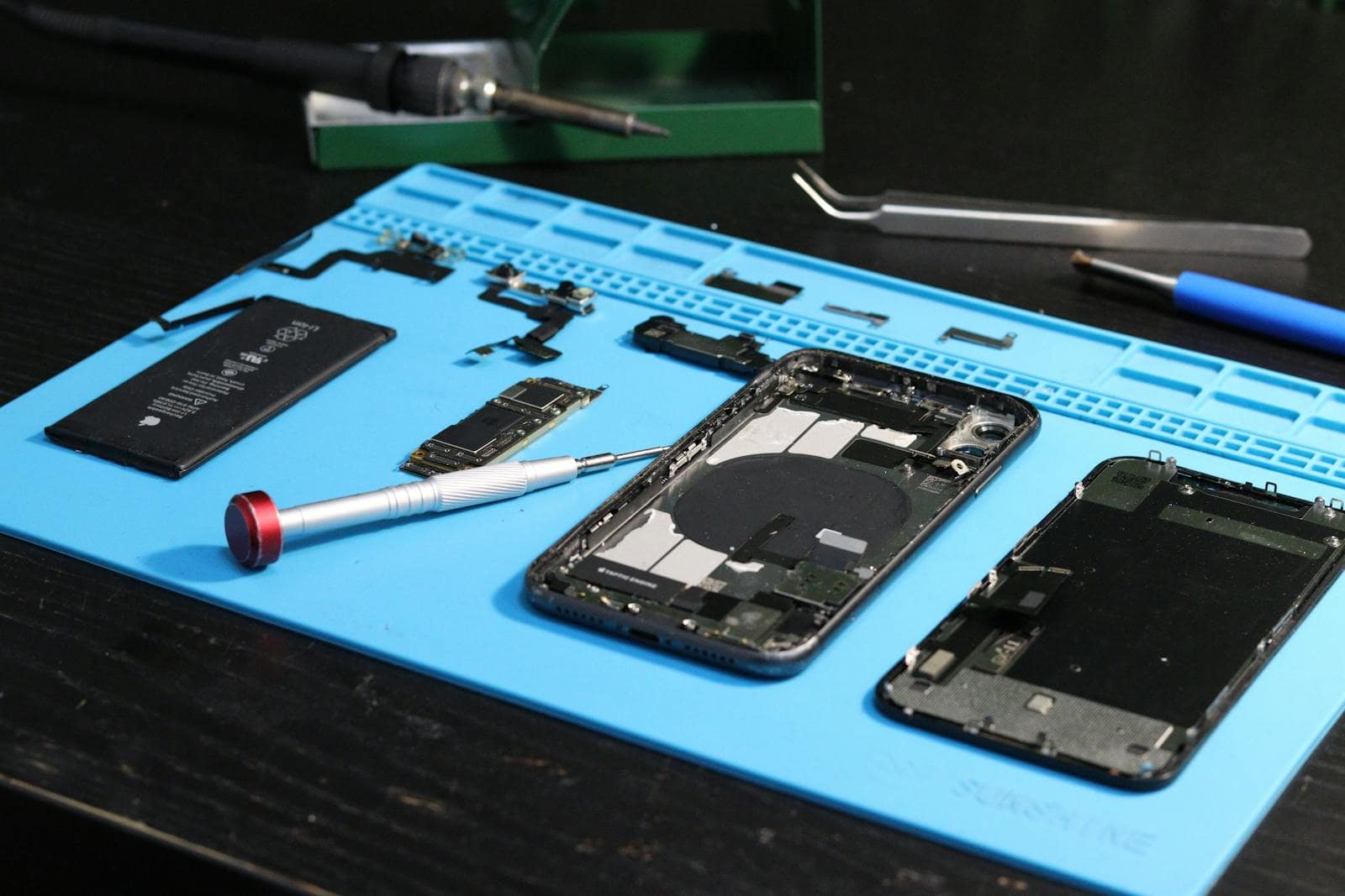 Disassembled smartphone components and repair tools on a workbench